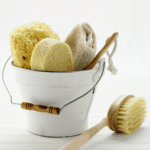 White bucket filled with cleaning supplies including sponges and brushes